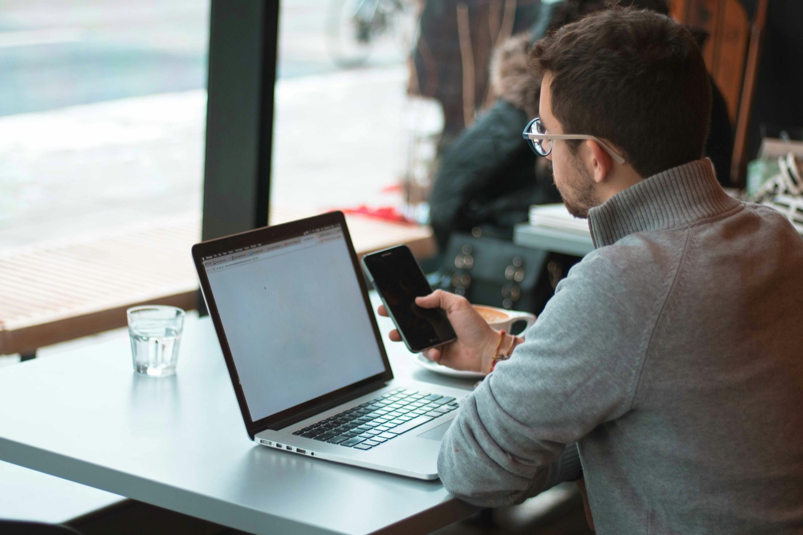 Focused business owner at a laptop by a window — the kind of decision-making moment that leads clients to DEM.