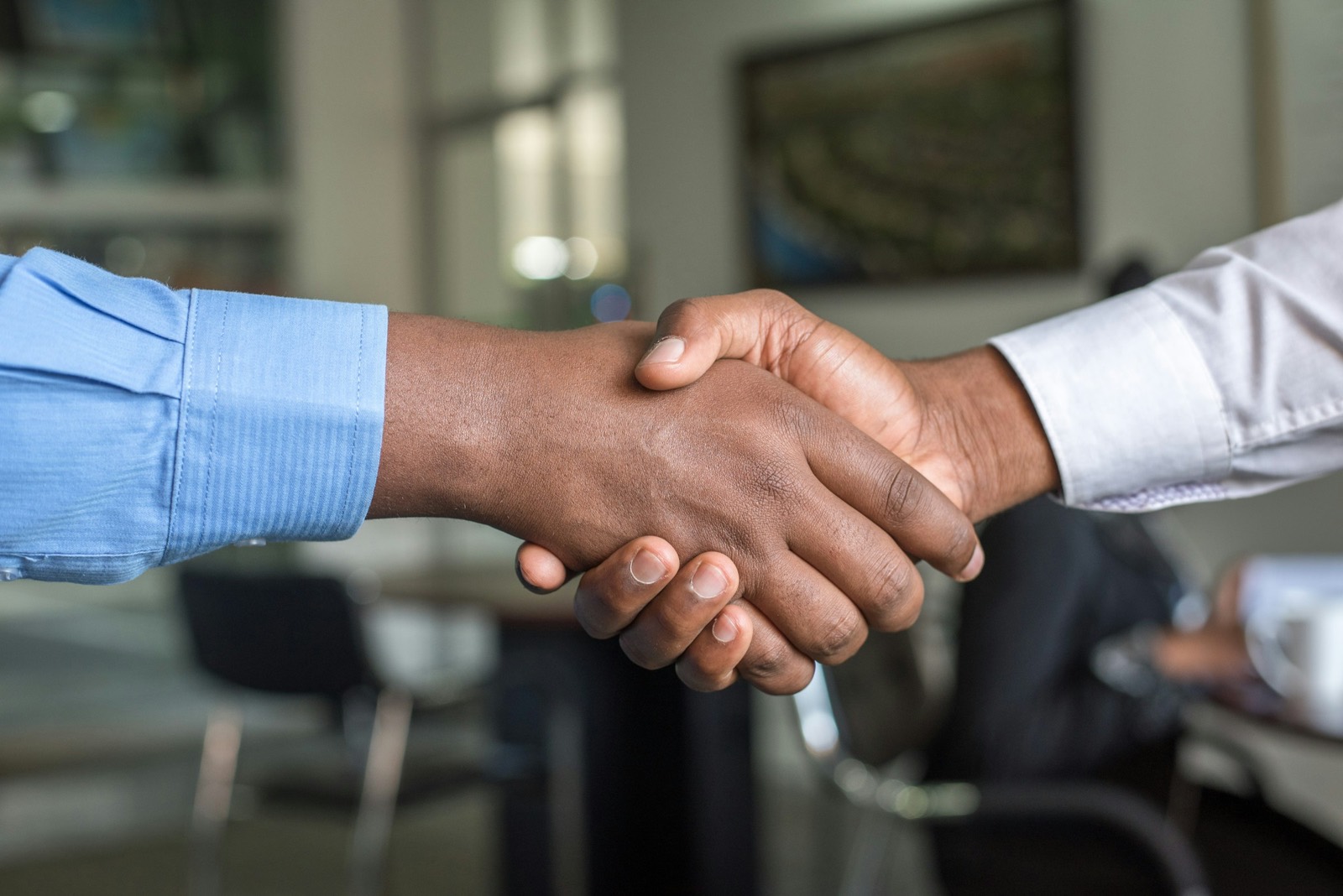 Two professionals shaking hands over a desk — the kind of trust-first client relationship this brokerage runs on.